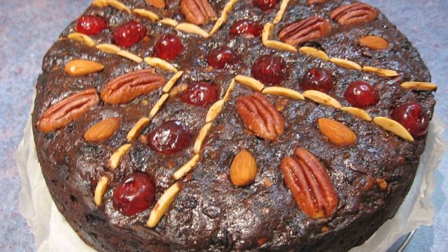 Rich fruit cake decorated with nuts and cherries