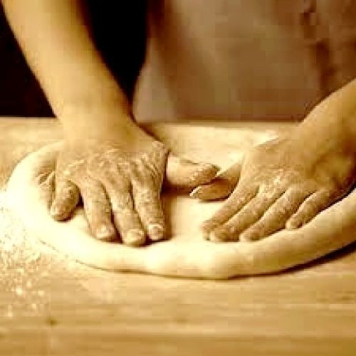 Pressing out the dough to fit the round pizza pan